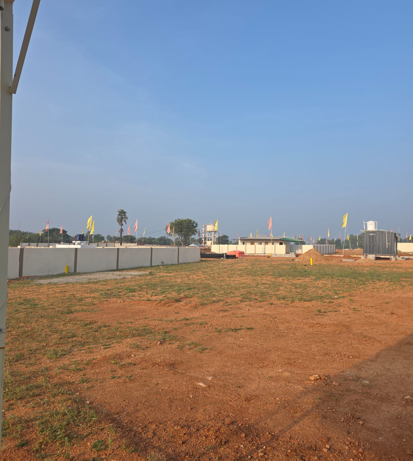 Levelled ground at Eastern Meadows with the compound wall, site office cabins and water tank in the distance