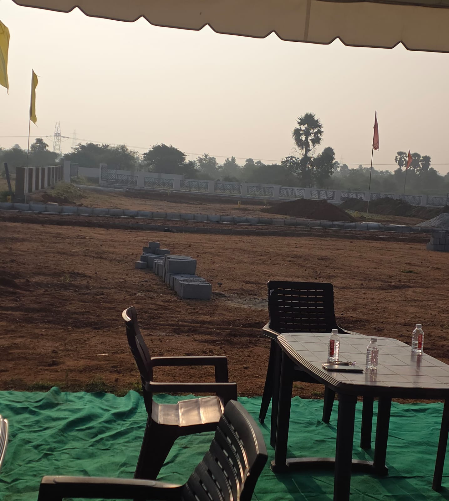 Seating under the site-visit tent at Eastern Meadows, with stacked kerb blocks and earthwork on the internal roads behind