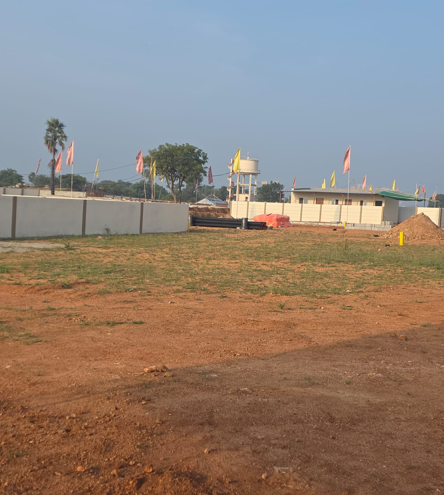 Eastern Meadows site office cabins and overhead water tank beyond levelled plots and the compound wall