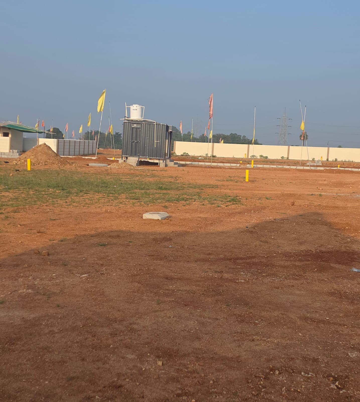 Eastern Meadows layout with a gravel stockpile, site office and water tank, and the compound wall behind